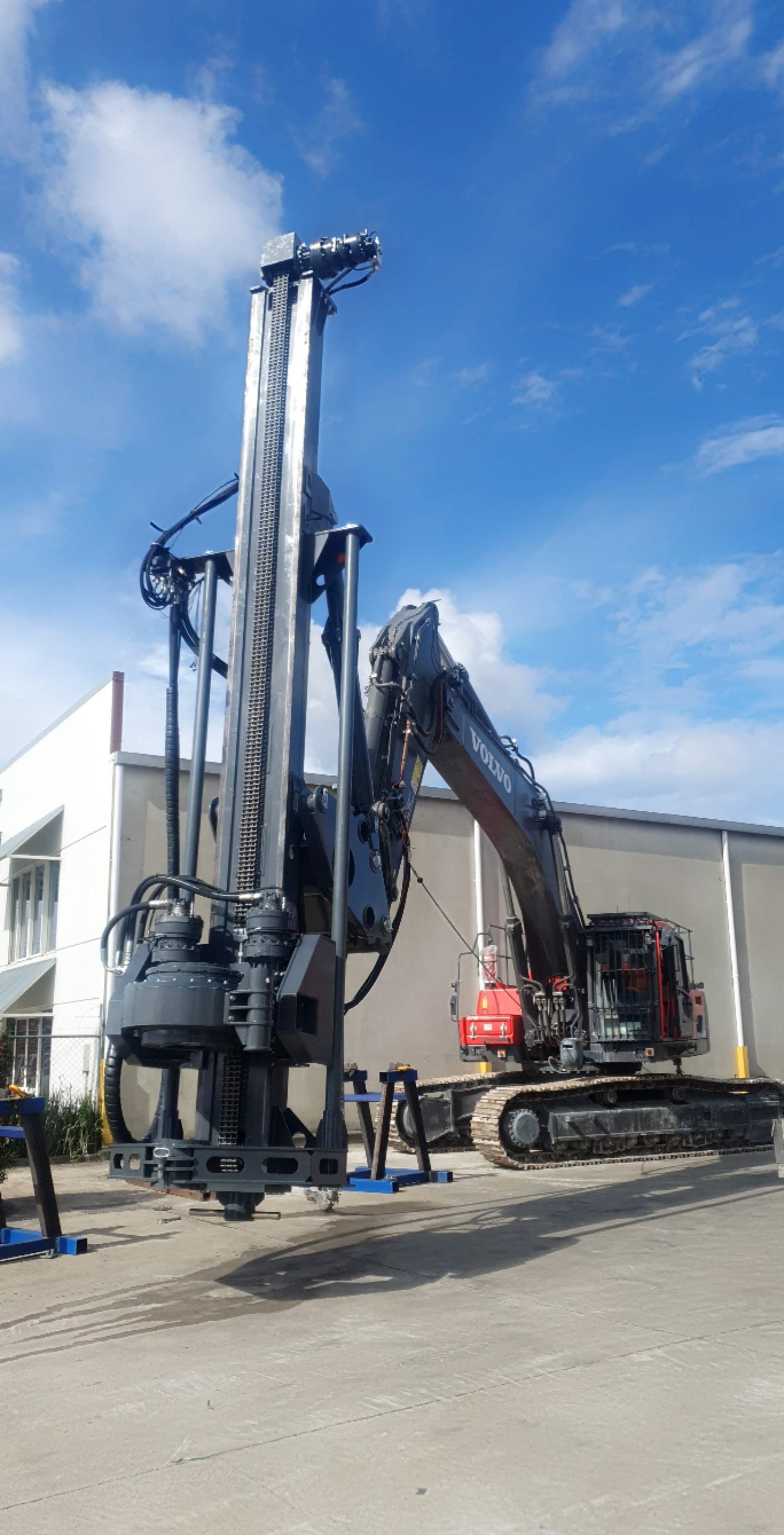 Excavator attachment mast with vertical sliding rotary head and hydraulic tilt cylinder